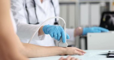 Ultrason teknisyeni genç bir kadının el ve el kemiklerini inceliyor. Ultrason kullanarak bileğin avuç içi yüzeyinin incelenmesi