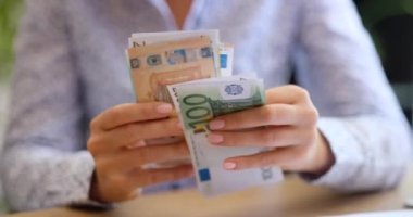 Kadın nakit avroluk banknotlarla para sayıyor. Kâr geliri ve aile bütçesi kavramı
