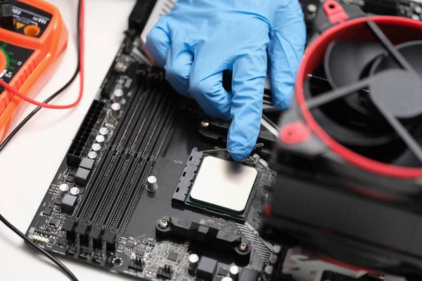 Man assembles components to build computer. Engineer puts processor on motherboard with socket