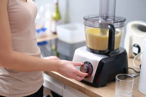 Woman presses start of food processor with dough. Blender for mixing food concept