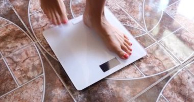 Woman measures weight on scales in morning. Overweight and measurement of body fat concept
