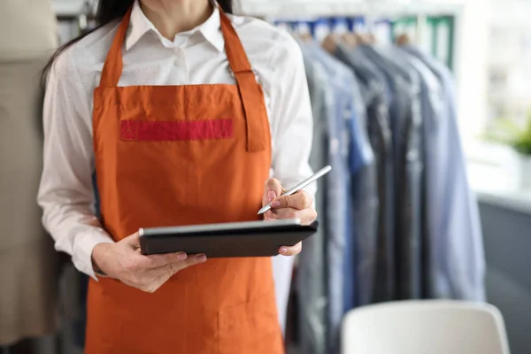 Dry cleaning administrator holds tablet with documents to sign. Laundry service concept