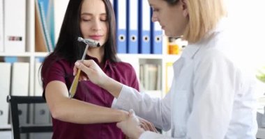 Tıbbi uzman kadın hasta konseptinin nörolojik tepkilerini kontrol ediyor. Doktor nörolog hastayı çekiçle muayene ediyor.
