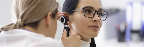 Portrait of doctor check patients ear on medical examination with special tool. Appointment in clinic at otolaryngologist specialist. Healthcare concept