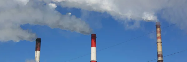 Close-up of smoking pipes of heating plant supplying heat to city, power station with three smoke stacks. Air pollution, ecology and production concept