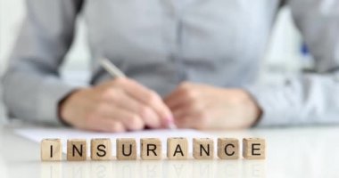 Masadaki tahta küpler, yazı sigortası, yakın plan. Kalemle yazan kadın ajan, sığ odaklı.