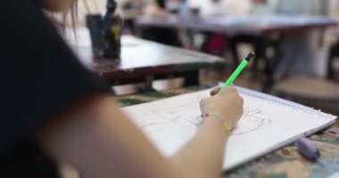 The girl in the class draws in the album, shallow focus. Teaching children the fine arts, kindergarten