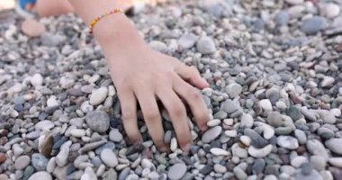 Kumsalda çakıl taşı toplayan bir gencin elleri, yakın plan, yavaş çekim. Denizde dinlen, sükunet