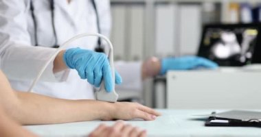Kadın bir doktor kolun ultrasonunu çeker, yakından, yavaş çekimde. Eldeki damarların hastalıklarının teşhisi