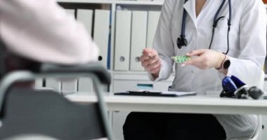 Doktor, tekerlekli sandalyedeki bir hastaya ilaç yazıyor. Yakın plan. Travma uzmanına danışma, yaralanmadan sonra rehabilitasyon.