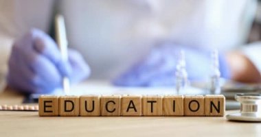 On the table in the clinic, wooden cubes with the inscription education, close-up. Medical training of students