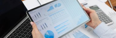 Ofisteki tabletteki dijital kağıtları inceleyen işçilere yakın çekim. Ofiste vasıflı bir işçi, evrakların dağınıklığı üzerine tablet. İş, istatistik kavramı
