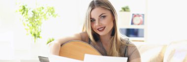 Güzel kadın müzik bestecisinin portresi, makyajlı sarışın, kameraya bak. Notalar önde dursun. Konser, müzikal performans, prova konsepti