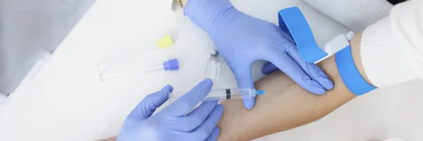Top view of nurse injects liquid medication in womans vein with needle. Qualified medical worker take blood with syringe for test. Medicine, health concept