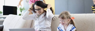 Portrait of happy woman working and playing with her kids on couch. Mother work from home, earn money for children. Parenthood, weekend, childhood concept