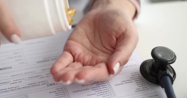 Bir kadın eli avuç içine jöle sarısı kapsüller döker, yakın plan. Beslenme takviyeleri, antioksidanlar.