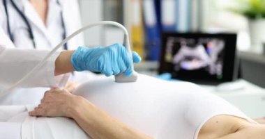 Hamile bir kadının karnına sonda takmış bir doktor, yakın plan. Hamileliğin sonlarına doğru ultrason, doğum hazırlığı.