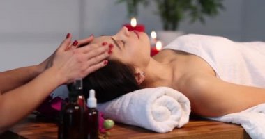 The hands of a masseuse in the salon stroke the forehead of a woman, close-up. Thai head and face massage