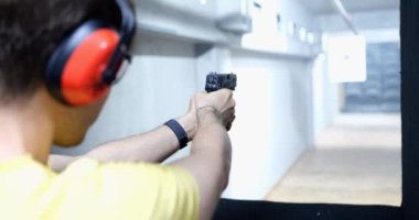 Atış poligonunda bir adam nişan alır ve ateş eder, yakın plan. Güvenlik personeli ve koruma eğitimi