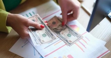 Ofisteki bir kadın dolar sayıyor, yakın çekim eller, yüzeysel odaklanma. Tamamlanan proje için ödeme, maaş