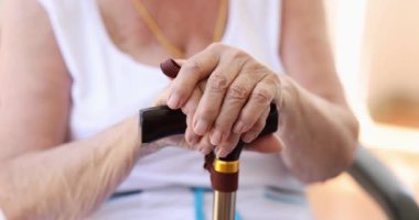 Elinde baston olan yaşlı bir kadının ellerinde çocuk elleri, yakın plan. Aile ilişkisi. Torun ve büyükanne.