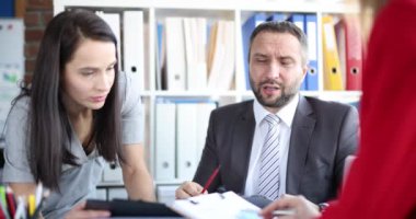 A male boss at the table speaks with female employees, close-up. Informal communication in the office