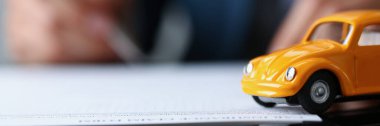 Masanın üzerindeki araba sigortası kağıdına yakın çekim, belgede sarı minyatür. Sözleşmeyi imzala ve arabanı kazadan koru. Araç sigortası kavramı