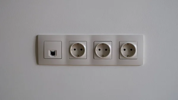 Electric socket on white wall closeup. Sockets with antenna cable and internet concept