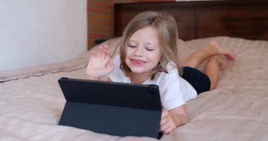 Küçük kız elini dijital tablete sallıyor ve video bağlantısı ile iletişim kuruyor. Çocuklar için mobil uygulama kavramı