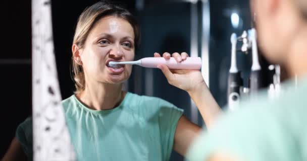 Młoda Kobieta Myjąca Zęby Elektryczną Szczoteczką Zębów Przed Filmem Lustrze — Wideo stockowe