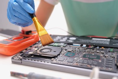 Bakım dizüstü bilgisayarı mühendisi elinde toz fırçası tutuyor. Bilgisayar devre kartlarının dizüstü bilgisayar konseptinde bakımı