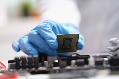 Computer engineers hand is holding cpu processor. Computer engineer assembles microprocessor processor into electronic motherboard chip concept