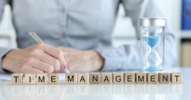 Bir kadın masada, tahta küplerin üzerine yazılar yazıyor. Yazıt zaman yönetimi, yakın çekim, yavaş çekim. Verimli ofis işi