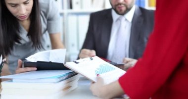 Ofisteki insanlar dokümanlara grafiklerle bakıyorlar, yakın plan. Düşen ekonomik göstergeler, piyasa çöküşü