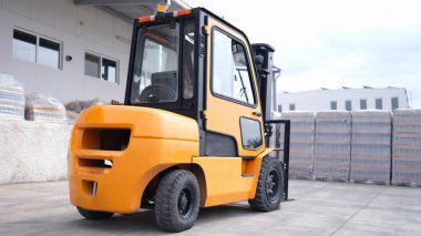 Reliable yellow forklift in warehouse. Worker ready to load pallets with skid steer loader concept
