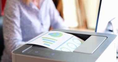 Secretary prints on printer financial indicators of analytics in charts. Preparation of statistics in marketing concept
