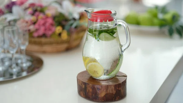 Infused detox water with cucumber, lemon and mint in jug on table. Diet healthy eating and weight loss concept