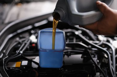 Pour gear oil into car through watering can. Replacement of technical fluids in car