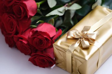 Red rose flowers and gift box on table. Womens day and birthday celebration concept