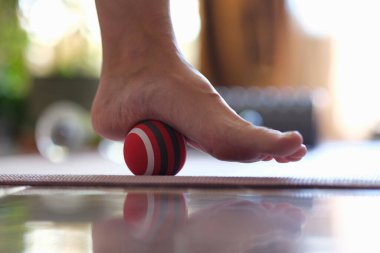 Massage ball applies pressure to painful area on foot. Self-massage and exercises with massage ball for legs concept