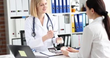 Woman cosmetic surgeon shows patient samples of breast implants and tells plastic surgery. Breast augmentation and lift concept