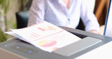 Office worker prints paper on multifunctional laser printer. Financial analytics and statistics documents and printing technology