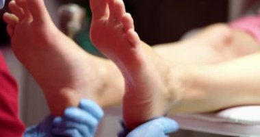 Female pedicurist makes foot massage in beauty salon closeup. Cosmetic procedures for feet concept