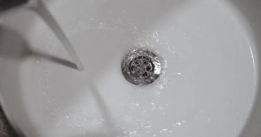 White sink flowing clean tap water closeup. Bath plumbing and wastewater treatment concept