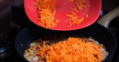 Cooking fried carrots in pan with onions. Homemade vegetarian food concept