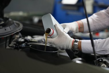 Mechanical filling of oil into car in repair garage. Changing oil in engine of car service center