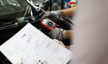 Mechanical service using multimeter to check voltage level in car battery and auto documentation diagram. Car diagnostics in car service