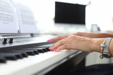 Female hand presses keys of synthesizer and learns to play. Piano lessons concept