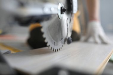 Master cutting piece of laminated wood shelves with manual electric saw in apartment. Laminate cutting machine concept