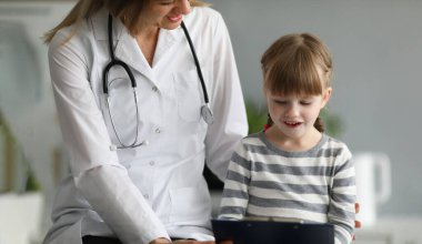 Little beautiful girl communicates with female doctor in clinic. Concept of children medical services and insurance